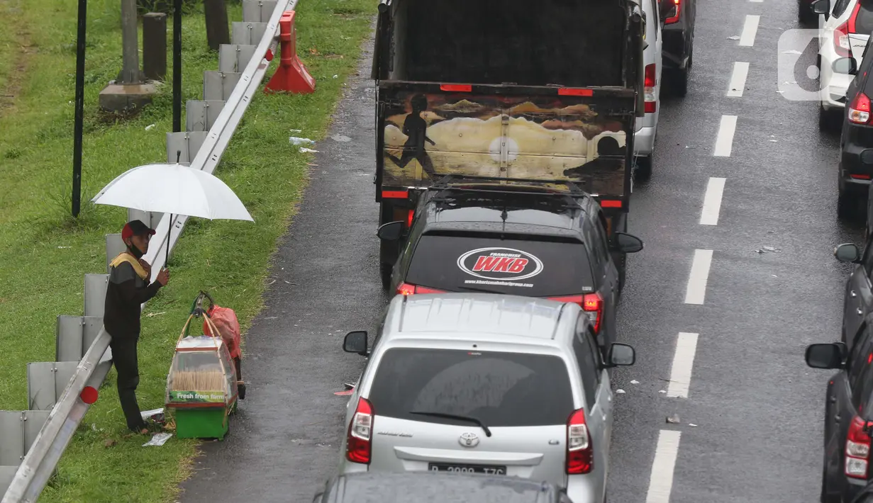 Seorang pedagang asongan menawarkan dagangan kepada pengendara di jalan tol Jagorawi yang sedang menanti waktu buka tutup jalur menuju kawasan wisata puncak, Bogor, Jawa Barat, Sabtu (31/10/2020). (Liputan6.com/Helmi Fithriansyah)