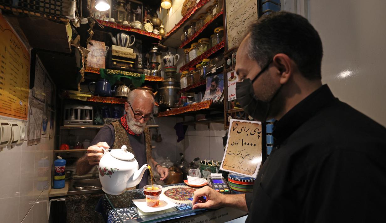 Pemilik Kazem Mabhutian (63) menyajikan teh di kedai teh terkecil dan tertua di gang Grand Bazaar di ibukota Iran, Teheran (20/9/2021).  Di sela-sela menuangkan segelas teh untuk pelanggannya, Kazem memberi tahu kisah seabad tentang Rumah Teh Haj Ali Darvish dengan bangga. (AFP/Atta Kenare)