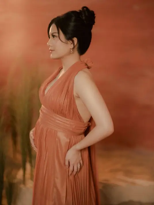 Valencia Tanoesoedibjo juga lakoni maternity shoot. Di foto ini, ia tampil menawan mengenakan dress oranye dengan detail halter-neck. [Foto: Instagram/valenciatanoe]