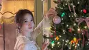 Yoona berpose di depan pohon Natal yang dihiasi dengan banyak pita. Ia tampil mengenakan atasan lengan panjang lace dipadukan kalung mutiara. [@yoona_lim]