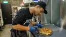 Seorang anggota staf menyiapkan pizza rasa durian di kafe Mao Shan Wang di distrik Chinatown, Singapura (24/1). (AFP Photo/Nicholas Yeo)