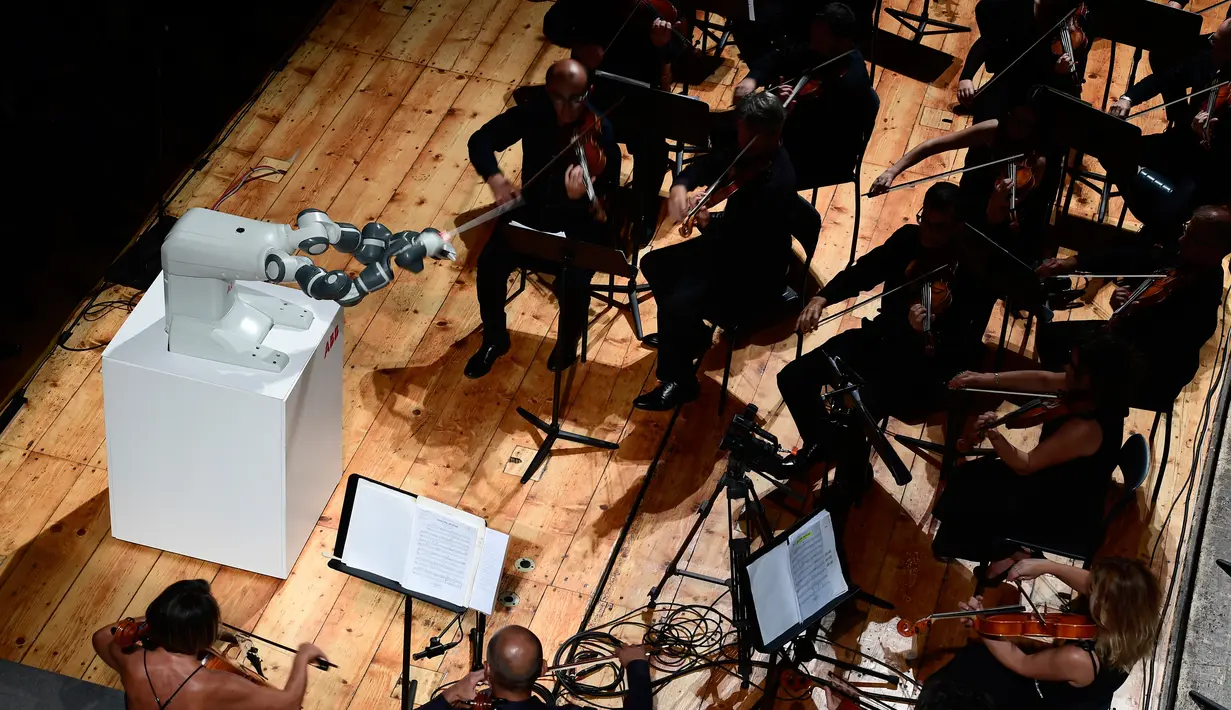 Robot Humanaid YuMi saat memimpin konser Lucca Philharmonic Orchestra di The Teatro Verdi di Pisa, Italia (12/9). Robot YuMi dibuat di Swiss dengan satu lengan memegang tongkat dan lengan lainnya memacu senar. (AFP Photo/Miguel Medina)