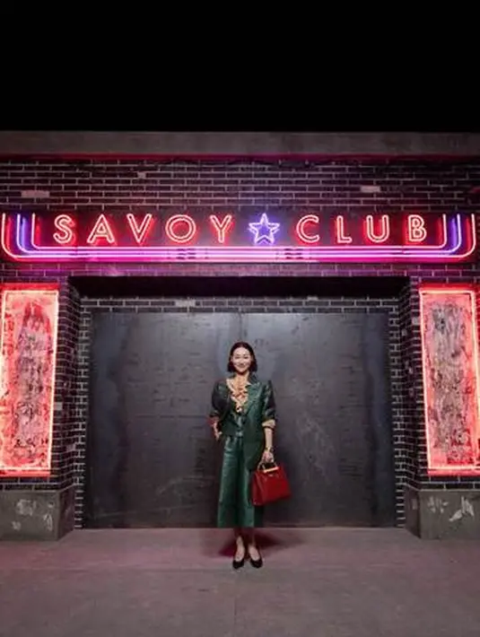 Hui Yinghong mengenakan Gucci Ouverture look 72 berwarna hijau dan multicolor mini GG Wool Lurex Two Button Jacket. Dipadukan dengan kemeja lengan panjang crepe satin yag memiliki detail ruffle. Celana kulit G Wool muliwarna, heels hitam, dan tas Gucci Diana melengkapi penampilannya yang colorful