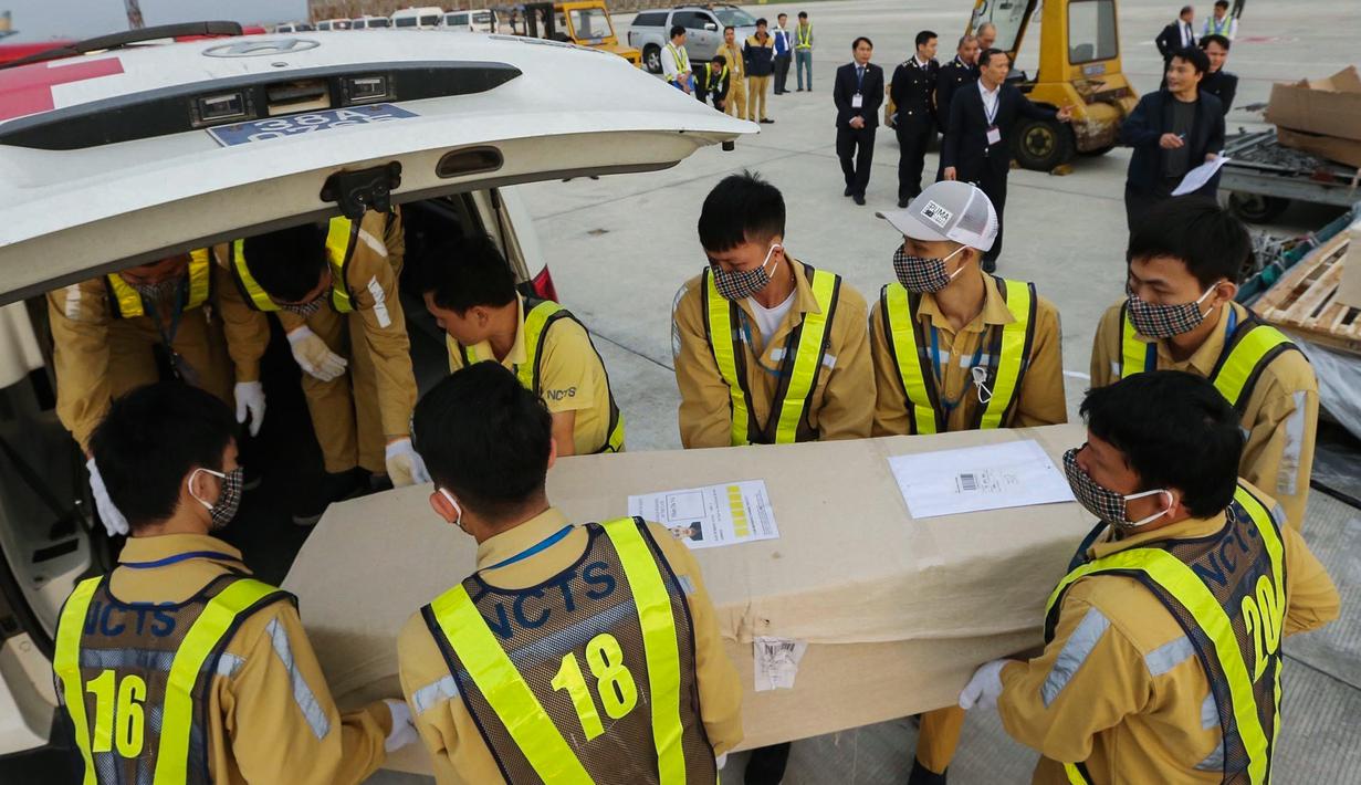 Petugas memasukkan peti mati berisi jenazah yang ditemukan tewas dalam truk kontainer di Inggris ke dalam ambulans setibanya di bandara internasional Noi Bai, Hanoi, Rabu (27/11/2019). Sebanyak 16 dari 39 jenazah telah tiba di Vietnam untuk dibawa ke kampung halaman masing-masing. (Nhac NGUYEN/AFP)