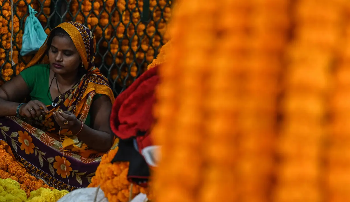 Seorang wanita membuat karangan bunga jelang Festival Diwali di pasar bunga New Delhi, India, Minggu (31/10/2021). Festival Diwali atau Festival Cahaya dalam agama Hindu melambangkan kemenangan baik atas buruk. (Money SHARMA/AFP)