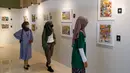 Pengunjung mengamati karya lukis yang bertajuk 'Membangun Harmoni' di Museum Basoeki Abdullah, Jakarta, Sabtu (18/12/2021). Pameran tersebut dibisa disaksikan dari 19 Desember 2021 hingga Januari 2022. (Liputan6.com/Herman Zakharia)