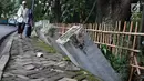 Warga melintas di samping pagar yang ambruk di Taman Hutan Tebet, Jakarta, Kamis (28/3). Pagar yang ambruk tidak diperbaiki melainkan diganti menggunakan bambu. (Liputan6.com/Immanuel Antonius)