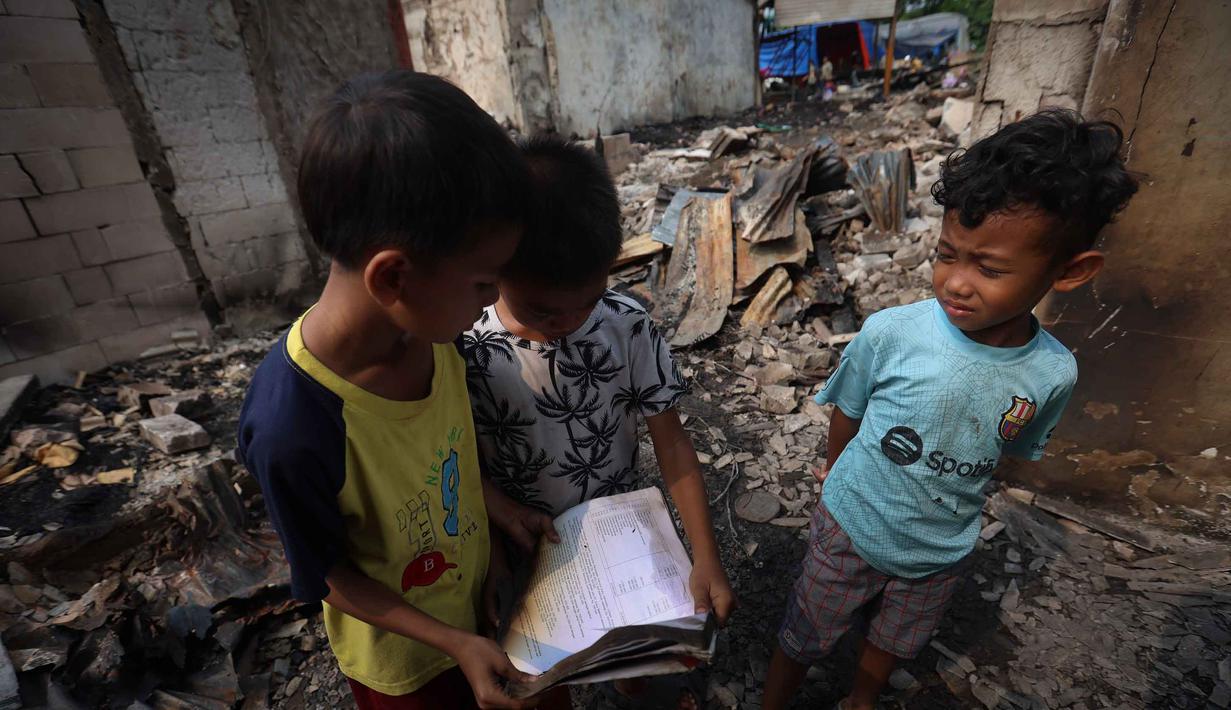 Tiga orang anak memandang sisa lembar kertas nan terbakar di letak jejak kebakaran di permukiman padat masyarakat di Jalan Kemayoran Gempol belakang Pasar Jiung, Kelurahan Kebon Kosong, Kecamatan Kemayoran, Jakarta Pusat, Selasa (2/6/2026). (Kapanlagi.com/Budy Santoso)