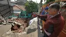 Seorang warga mengambil gambar kondisi tanah longsor di Perumahan Pesona Kalisari, Pasar Rebo, Jakarta, Selasa (27/11). Intensitas hujan yang tinggi mengakibatkan sebidang tanah di wilayah tersebut longsor. (Liputan6.com/Herman Zakharia)