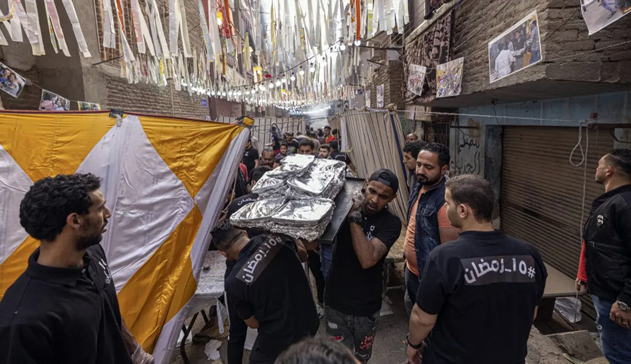 Relawan bersiap untuk menyajikan makanan buka puasa massal pada hari ke-15 bulan suci Ramadhan di pinggiran Matariya, timur laut Kairo, Mesir, 16 April 2022. (Khaled DESOUKI/AFP)