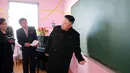 Kim Jong Un berbincang dengan para staf sekolah saat mengunjungi Sekolah Dasar Anak Yatim di Pyongyang (2/2). (AFP Photo / KCNA VIA KNS / STR)