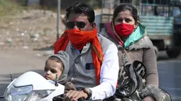 Seorang pria mengendarai skuter dengan syal yang menutupi wajahnya sebagai pengganti masker wajah di Ahmedabad, India, 12 Januari 2022. Beberapa pemerintah daerah, seperti yang ada di ibu kota New Delhi, telah merekrut staf baru untuk memastikan aturan wajib masker dipatuhi. (AP Photo/Ajit Solanki)