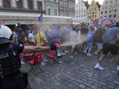 Para polisi menyemprotkan semprotan merica untuk membubarkan kericuhan antar fans menjelang laga final Conference League 2024/2025 antara Real Betis melawan Chelsea di sekitar restoran kota Wroclaw, Polandia, Selasa (27/05/2025) waktu setempat. (AP Photo/Czarek Sokolowski)