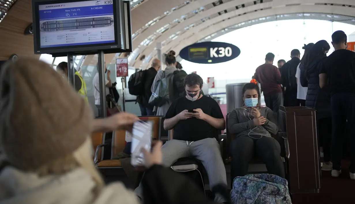Penumpang menunggu untuk naik pesawat ke New York di bandara Charles de Gaulle, utara Paris, Senin (8/11/2021). Pencabutan pembatasan perjalanan memungkinkan wisatawan untuk melakukan perjalanan yang lama tertunda. (AP Photo/Christophe Ena)