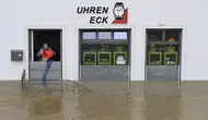 Seorang pria mencoba menumpahkan air dengan ember dari toko arlojinya di jalan dan rumah-rumah yang tergenang banjir di pusat kota Passau, Bavaria, wilayah selatan Jerman, pada 4 Juni 2024. (Michaela STACHE/AFP)