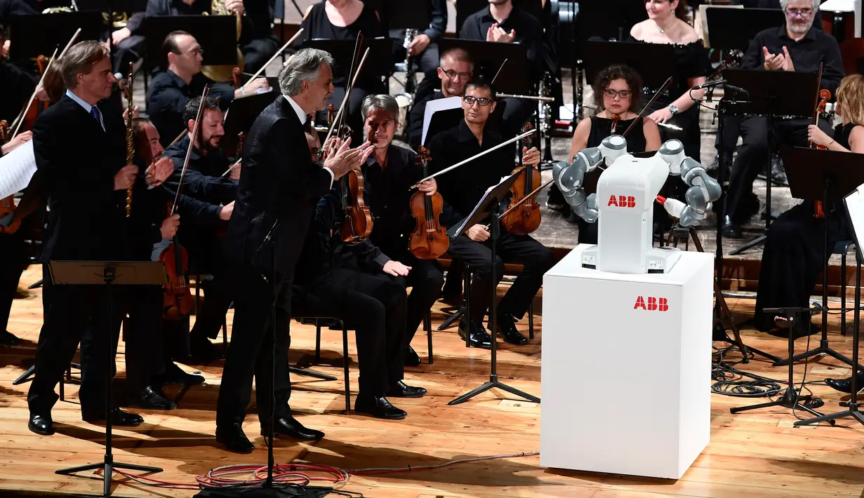 Penyanyi tenor Italia Andrea Bocelli dan robot YuMi saat tampil dalam konser Lucca Philharmonic Orchestra di The Teatro Verdi di Pisa, Italia (12/9). Robot YuMi dirancang oleh pemimpin robotika ABB. (AFP Photo/Miguel Medina)