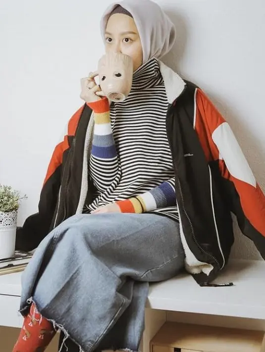 Kali ini, Gita memadukan turtleneck motif stripe dengan jaket parasut. Tampilannya dipermanis dengan rok jeans. (Instagram/gitasav).