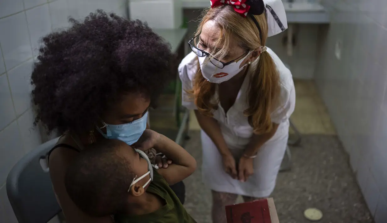 Seorang perawat menghibur anak setelah disuntik dengan dosis vaksin COVID-19 Soberana-02, di sebuah klinik di Havana, Kuba, Kamis (17/9/2021). Pemerintah Kuba memulai vaksinasi Covid-19 bagi anak-anak berusia 2 tahun dengan vaksin buatan dalam negeri. (AP Photo/Ramon Espinosa)
