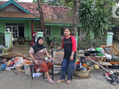 Keluarga ibu Haji Mamah Rusmahwati berpose di depan kediamannya Desa Sumber Urip Pebayuran, Kabupaten Bekasi, Jawa Barat, Senin (22/2/2021). Banjir merenda keluarga tersebut merapikan barang-barang dan bersihkan rumah yang sudah surut. (Liputan6.com/Herman Zakharia)