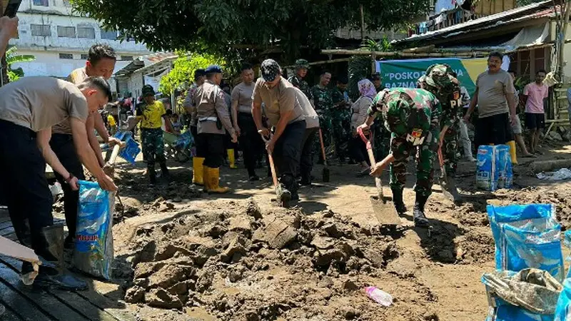 Personil TNI dan Polri, Senin (30/1/2023), membantu warga membersihkan material sisa banjir dan longsor di Manado.