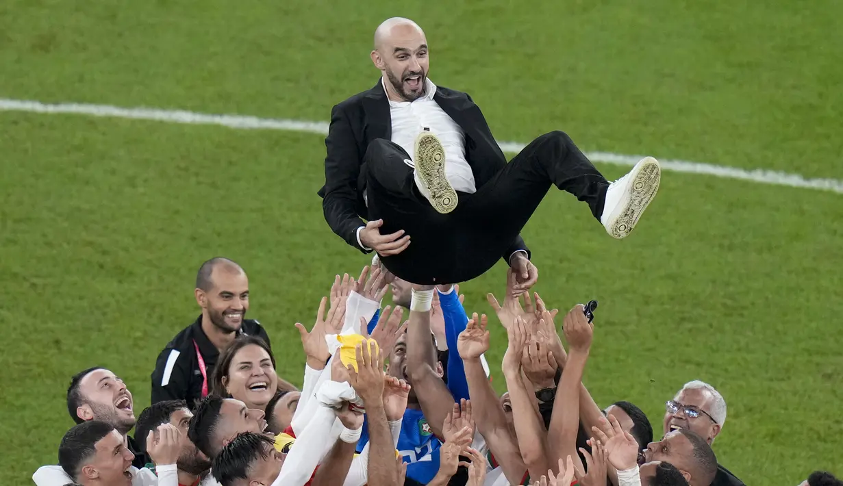 Para pemain Maroko melakukan selebrasi dengan melemparkan pelatih Walid Reragui ke udara usai pertandingan melawan Kanada pada grup F Piala Dunia 2022 di Stadion Al Thumama di Doha, Qatar, Kamis (1/12/2022). Hasil ini membuat Maroko lolos ke babak 16 besar Piala Dunia 2022 dengan status juara Grup F dengan perolehan tujuh poin. Sementara runner up jadi milik Kroasia. (AP Photo/ Alessandra Tarantino)