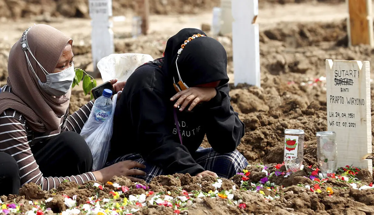 Seorang wanita menangis saat mengunjungi makam kerabat yang meninggal karena COVID-19 di TPU Rorotan, Jakarta, Rabu (7/7/2021). Di seluruh negeri, virus corona COVID-19 kembali menyebar dengan cepat dengan meledak di luar kapasitas dan pasokan oksigen habis. (AP Photo/Tatan Syuflana)