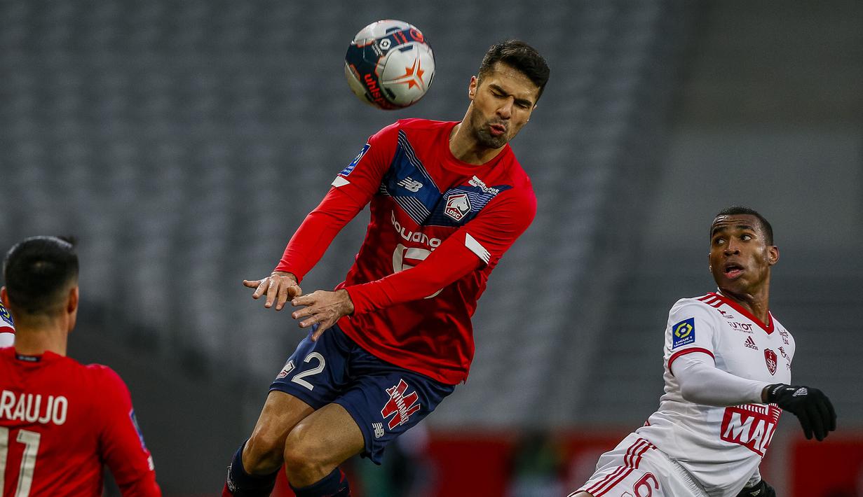 Bek Lille, Zeki Celik (tengah) berebut bola dengan gelandang Brest, Jean Lucas dalam laga lanjutan Liga Prancis 2020/21 pekan ke-25 di The Stade Pierre Mauroy, Lille, Minggu (14/2/2021). Lille bermain imbang 0-0 dengan Brest. (AP/Michel Spingler)