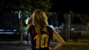 Seorang fans wanita mengenakan kaus replika nomor 10 Lionel Messi duduk di luar stadion Camp Nou di Barcelona (5/8/2021). Belum diketahui ke mana Messi akan berlabuh pada musim panas ini. (AFP/Pau Barrena)