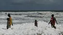 Penduduk setempat berjalan di atas limbah busa yang disebabkan polutan saat bercampur dengan ombak di pantai di Chennai (29/11/2019). Limbah busa tersebut  membuat penduduk dan pengunjung pantai merasa sakit. (AFP/Arun Sankar)