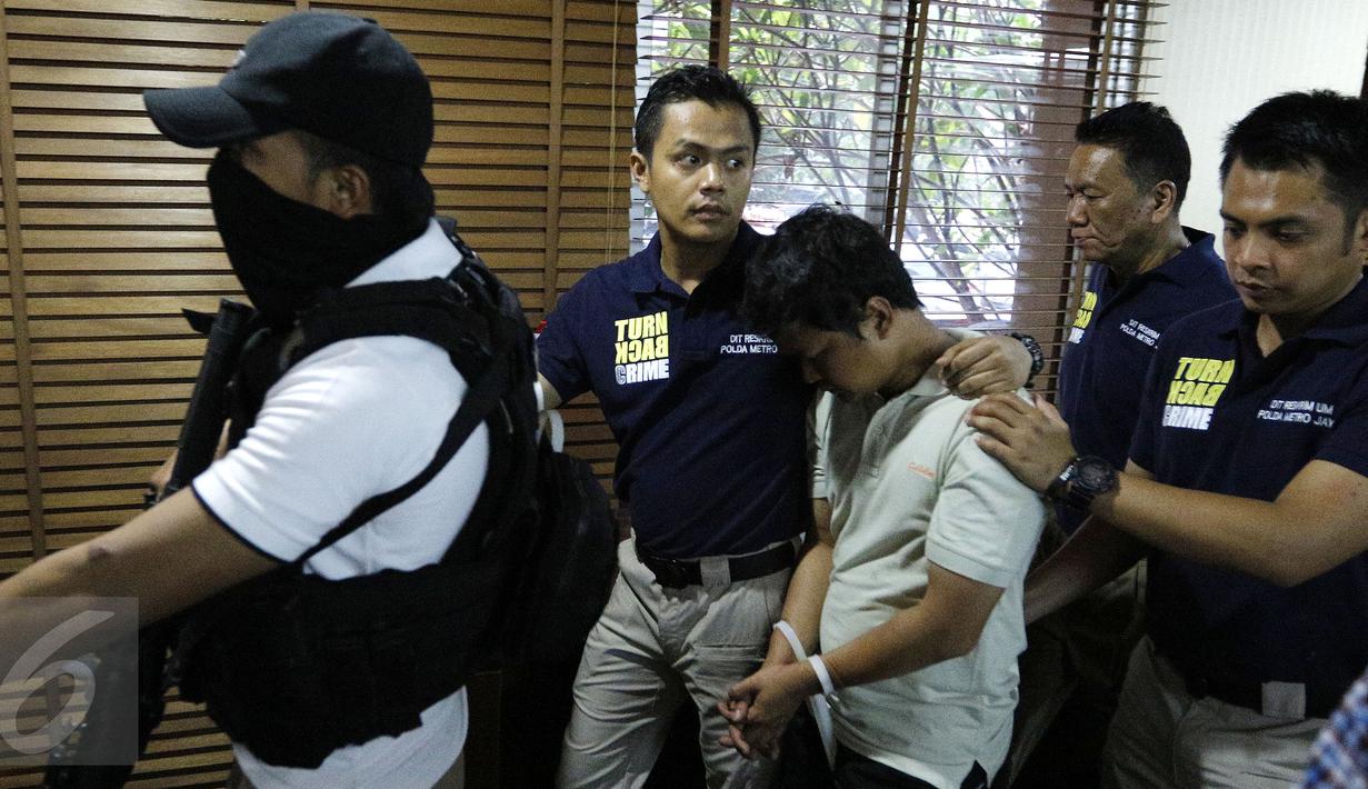 Petugas menggiring tersangka pelaku ledakan di Mall Alam Sutera berinisial LWK saat konferensi pers di Polda Metro Jaya, Jakarta, Kamis (29/10). LWK yang merupakan staf IT diduga melakukan pengebomannya atas dasar pemerasan. (Liputan6.com/Yoppy Renato)