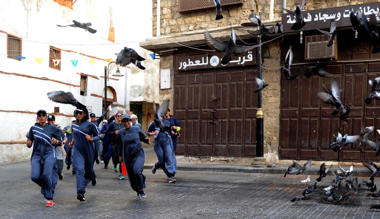 Perempuan Arab Saudi jogging dalam memperingati Women's Day atau Hari Perempuan Internasional di jalanan Distrik Al-Balad, Jeddah, Kamis (8/3). Kebijakan Putra Mahkota Mohammed bin Salman membuat banyak kebebasan bagi perempuan. (Amer HILABI/AFP)