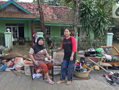 Keluarga ibu Haji Mamah Rusmahwati berpose di depan kediamannya Desa Sumber Urip Pebayuran, Kabupaten Bekasi, Jawa Barat, Senin (22/2/2021). Banjir merenda keluarga tersebut merapikan barang-barang dan bersihkan rumah yang sudah surut. (Liputan6.com/Herman Zakharia)