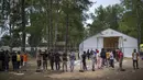 Para migran berdiri di pagar di kamp pengungsi yang baru dibangun di tempat latihan militer Rudninkai, Lithuania, Rabu (4/8/2021). Sekitar 4.090 migran, kebanyakan dari Irak, telah menyeberang tahun ini dari Belarus ke Lithuania. (AP Photo/Mindaugas Kulbis)