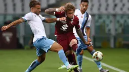 Penyerang Lazio, Ciro Immobile, berebut bola dengan pemain Torino pada laga lanjutan Serie A pekan ke-29 di Stadion Olimpico Grande Torino, Rabu (1/7/2020) dini hari WIB. Lazio menang 2-1 atas Torino. (AFP/Isabella Bonotto)