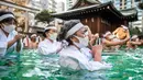 Penganut Shinto dari Kuil Teppozu Inari mandi dengan air dingin untuk mensucikan jiwa dan tubuh mereka selama ritual Tahun Baru di Tokyo, Jepang, Minggu (9/1/2022). Mereka melakukan prosesi mandi air dingin di sebuah bak yang telah disediakan oleh pihak kuil. (Philip FONG/AFP)