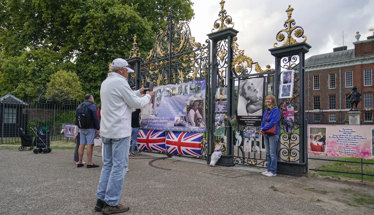 Seorang perempuan berfoto di dekat potret Putri Diana yang dipajang di gerbang Istana Kensington, di London, Senin, 29 Agustus 2022. Minggu ini, tepatnya pada 31 Agustus, menandai peringatan 25 tahun kematian Putri Diana dalam kecelakaan mobil di Paris. (AP Photo/Alberto Pezzali)