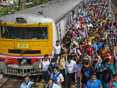 Komuter berjalan di sepanjang peron setelah keluar dari kereta lokal pinggiran kota di Kolkata, India, Senin (1/11/2021). Layanan kereta api kembali normal setelah menerapkan pembatasan yang diberlakukan sebelumnya untuk mengekang penyebaran corona Covid-19. (DIBYANGSHU SARKAR/AFP)