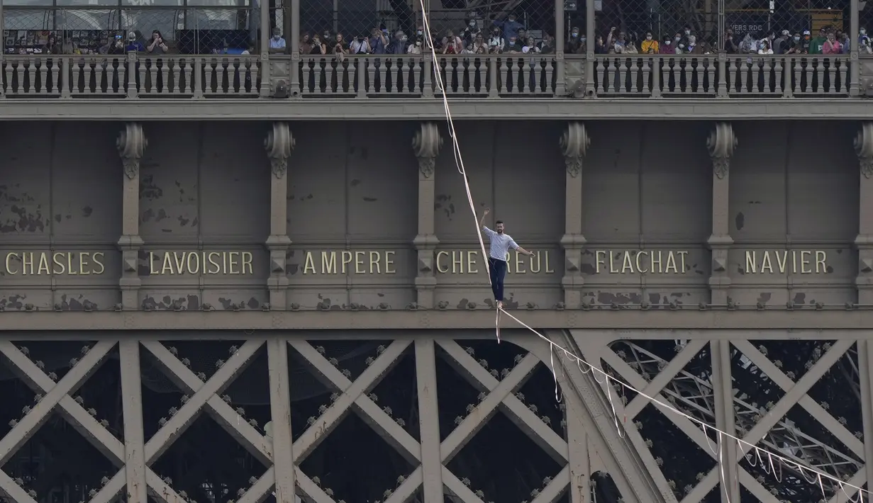 Akrobatik Nathan Paulin tampil untuk kedua kalinya meniti seutas tali slackline pada ketinggian 70 meter antara Menara Eiffel dan Theater Chaillot di Paris, Minggu (19/9/2021). Pada 2019, pria Prancis itu melakukan slackline walk setinggi 150 meter dengan panjang 510 meter. (AP Photo/Francois Mori)