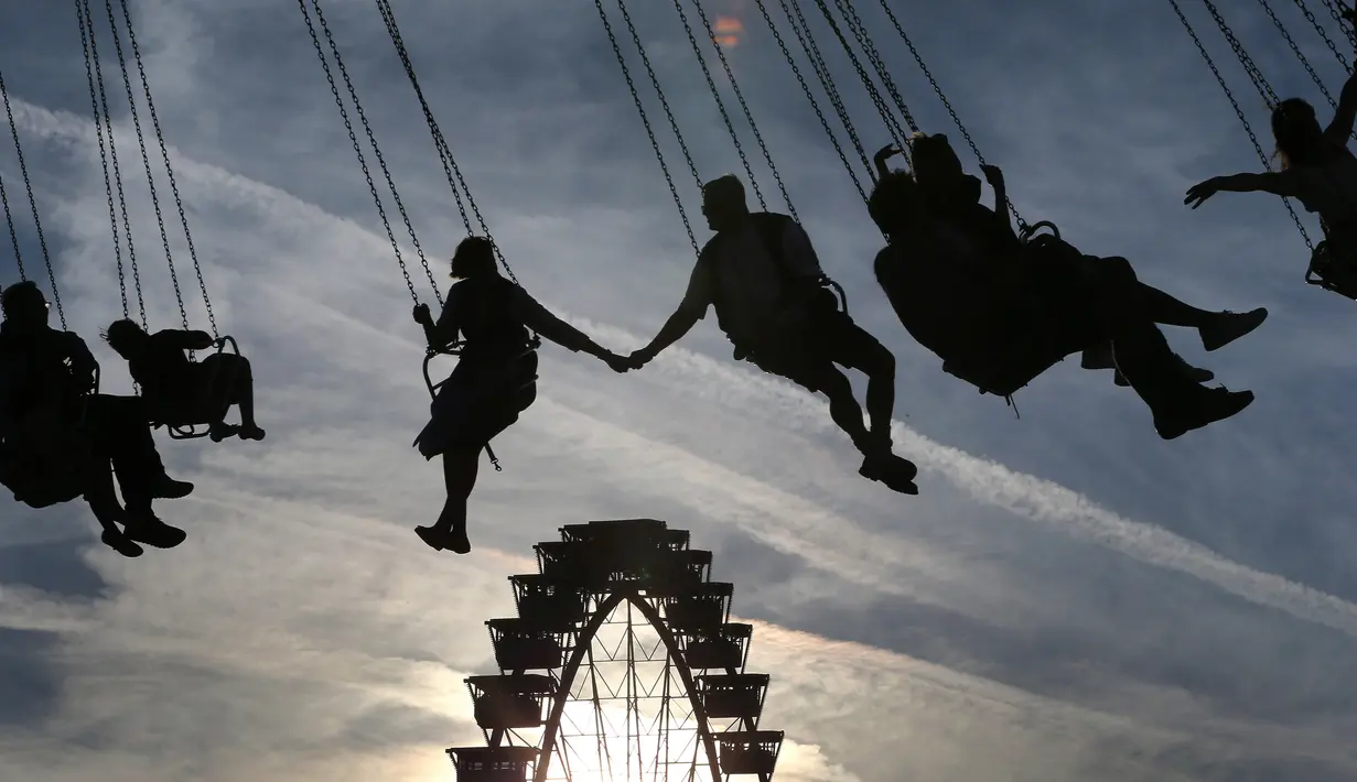 Pasangan kekasih berpegangan tangan saat menaiki komedi putar di festival bir terbesar di dunia Oktoberfest ke-185, Munich, Jerman, Sabtu (22/9). (Karl-Josef Hildenbrand/dpa /AFP)