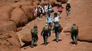 Wisatawan mendaki Uluru yang juga dikenal sebagai Batu Ayers di Taman Nasional Uluru-Kata Tjuta, utara Australia, Jumat (25/10/2019). Pendakian di Batu Ayers tersebut akan dilarang pada Oktober ini, seiring dengan keinginan Anagu, suku asli Aborigin yang mendiami kawasan tersebut. (SAEED KHAN / AFP)