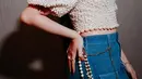 Atasan tersebut ia padukan dengan celana jeans high waist, menghadirkan perpaduan gaya klasik dan modern yang pas. Aksesori berupa kalung dan gelang mutiara senada pun menambah sentuhan manis pada keseluruhan look-nya.