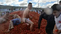 Peserta mengmbil tomat saat Festival Tomatina di Sutamarchan, Boyaca, Kolombia, Minggu (2/6/2019). Festival Tomatina ini sudah memasuki tahun ke-10. (Diana SANCHEZ/AFP)