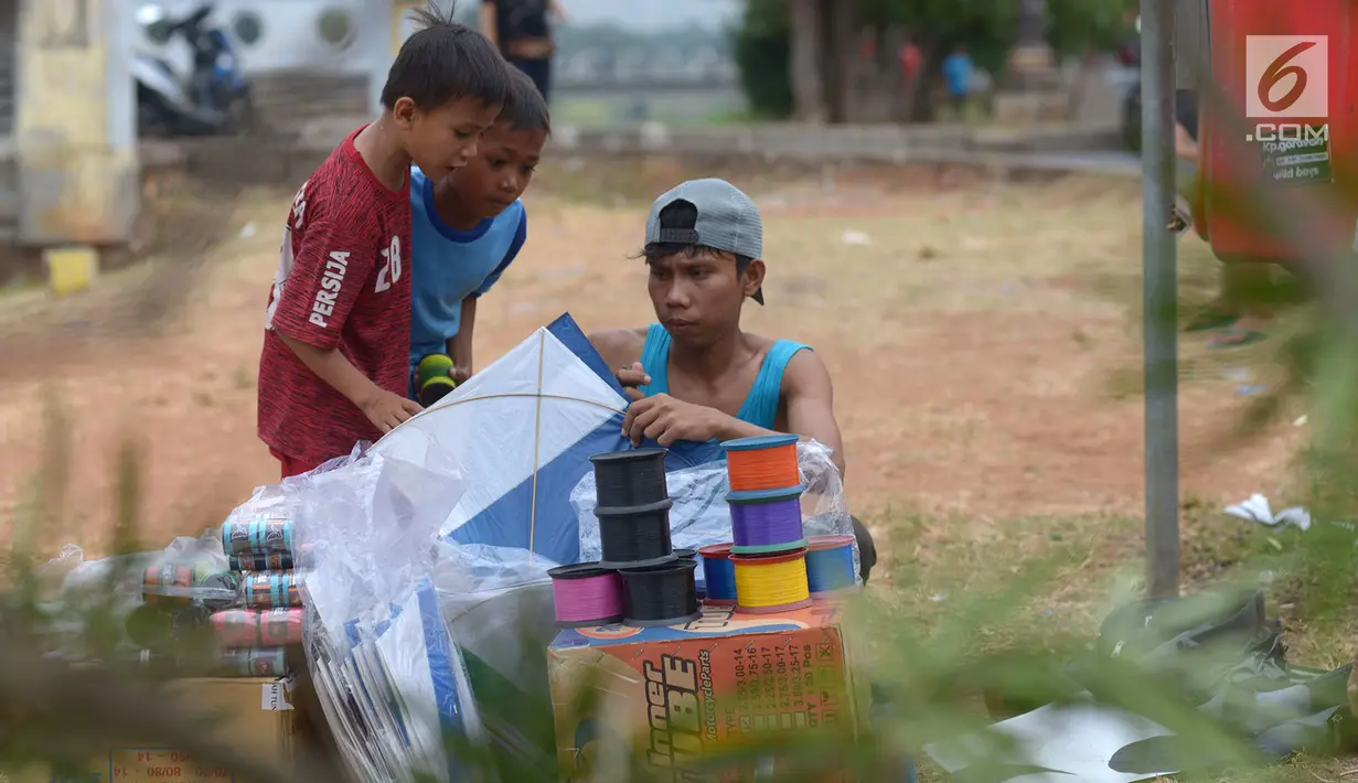 Pedagang layang-layang melayani pembeli saat berjualan di tepi Kanal Banjir Timur (KBT), Jakarta, Jumat (5/7/2019). Pedagang menjual layang-layang seharga Rp 1.000 per buah. (merdeka.com/Imam Buhori)