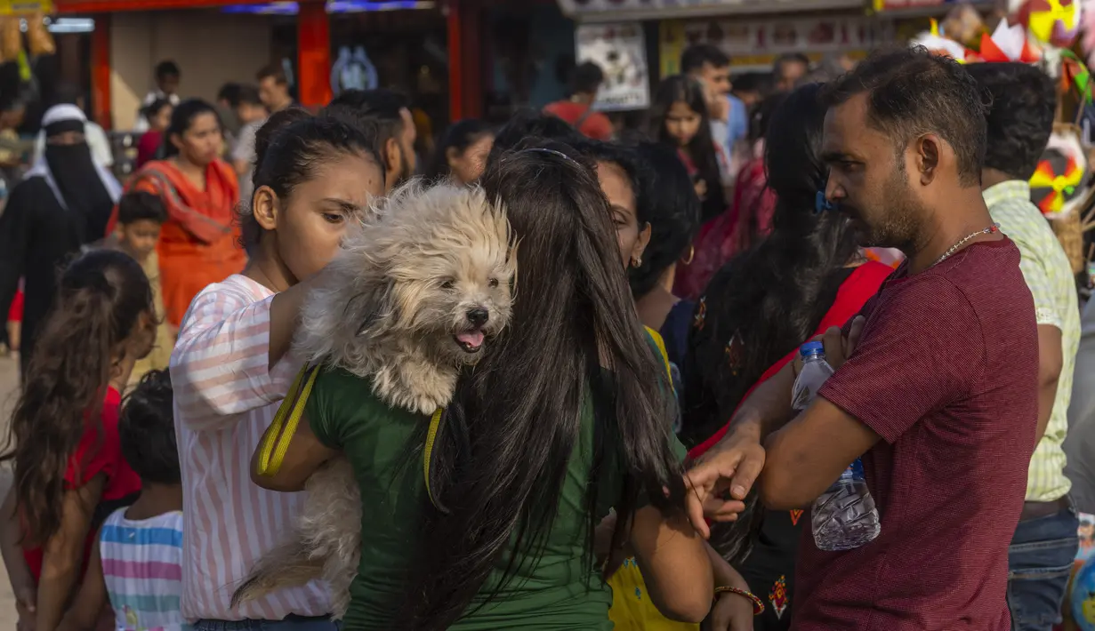<p>Seorang wanita membawa anjingnya saat orang-orang memadati pantai Juhu di Laut Arab pada hari yang panas dan lembab di kota Mumbai, India, 8 Mei 2022.&nbsp;Tingginya suhu udara diperparah dengan kurangnya curah hujan. Maret lalu tercatat sebagai bulan terpanas di India sejak 122 tahun lalu. (AP Photo/Rafiq Maqbool)</p>