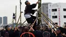 Seorang pemadam kebakaran memanjat tangga bambu setinggi 10 meter saat perayaan Tahun Baru di Tokyo, Jepang, Jumat (6/1). Mereka memperlihatkan berbagai aksi-aksi mendebarkan di atas bambu. (Toshifumi KITAMURA/AFP)