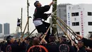 Seorang pemadam kebakaran memanjat tangga bambu setinggi 10 meter saat perayaan Tahun Baru di Tokyo, Jepang, Jumat (6/1). Mereka memperlihatkan berbagai aksi-aksi mendebarkan di atas bambu. (Toshifumi KITAMURA/AFP)