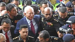 Mantan Perdana Menteri Malaysia, Najib Razak dengan pengawalan ketat tiba di Pengadilan Kuala Lumpur untuk didakwa pertama kalinya, Rabu (4/7). Najib sebelumnya telah ditangkap Komisi Anti-Korupsi Malaysia kemarin sore di kediamannya. (AP/Vincent Thian)