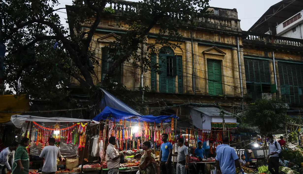 Warga melewati kios pinggir jalan yang menjual perlengkapan ibadah menjelang festival Hindu Chhath, di Kolkata, India  (9/11/2021). Selama Chhath, festival Hindu kuno yang populer di kalangan kelas pekerja, ritual dilakukan untuk berterima kasih kepada Dewa Matahari. (AP Photo/Bikas Das)