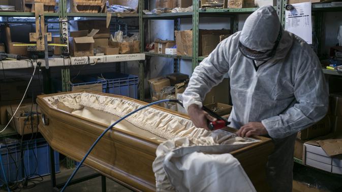 Pekerja menyelesaikan pembuatan peti mati di sebuah perusahaan di Ris Orangis, Prancis, Selasa (14/4/2020). Ketika virus corona COVID-19 menyerang Prancis, pembuat peti mati dan industri pemakaman lainnya bekerja keras untuk mengimbangi lonjakan permintaan. (AP Photo/Rafael Yaghobzadeh)