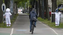 Pengendara sepeda menerima acungan jempol karena mengenakan helm dari seorang siswa berkostum astronaut, di Ring Street, Wina, Austria, Rabu (5/5/2021). Delapan siswa Wina berpartisipasi dalam acara itu untuk mengingatkan pengendara sepeda mengenakannya helm demi keamanan mereka. (JOE KLAMAR/AFP)